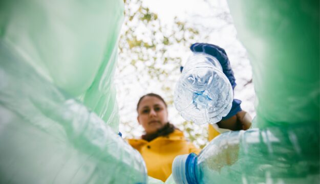 Eine Frau sammelt leere Plastikflaschen