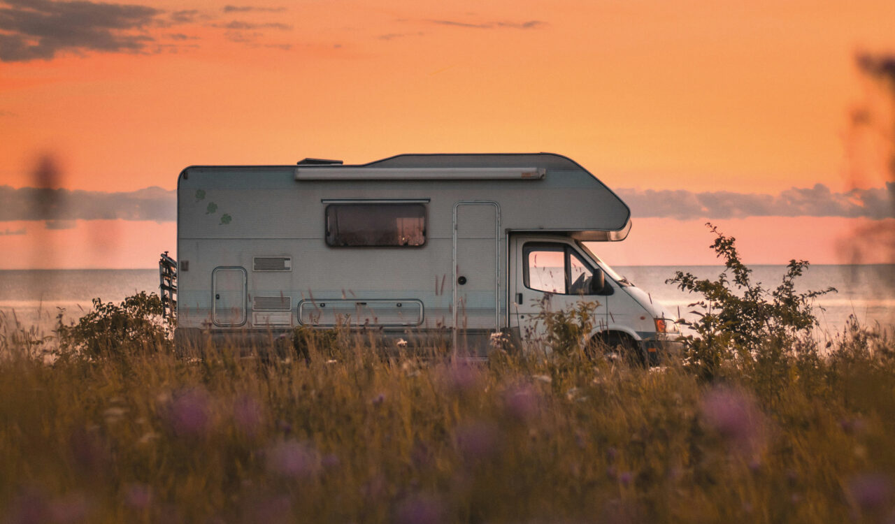 Ein Wohnmobil parkt vor einem rot-goldenen Sonnenuntergang