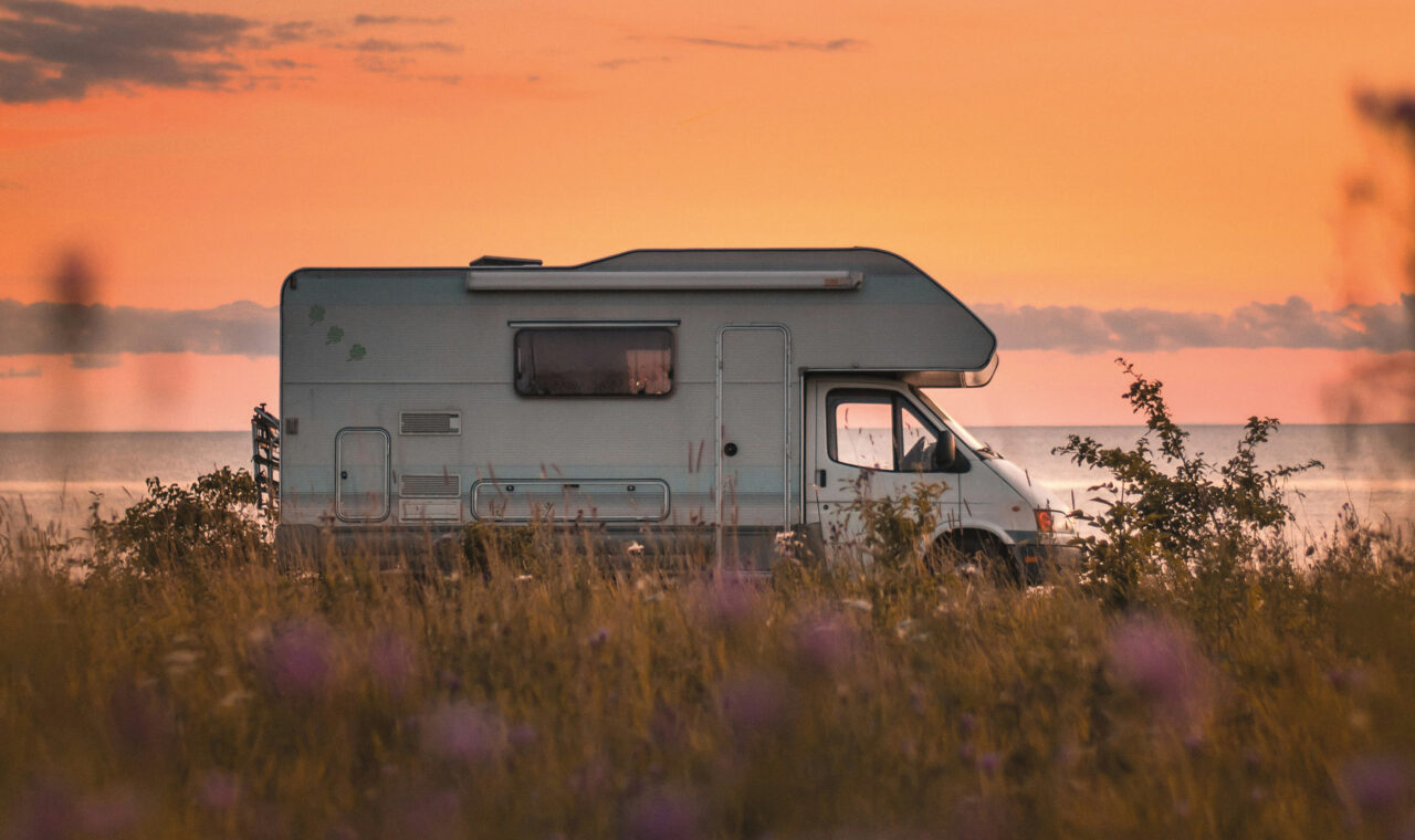 Ein Wohnmobil parkt vor einem rot-goldenen Sonnenuntergang