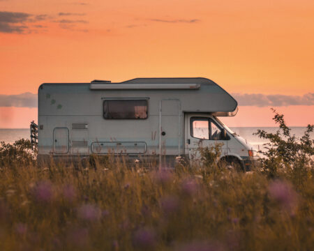 Ein Wohnmobil parkt vor einem rot-goldenen Sonnenuntergang