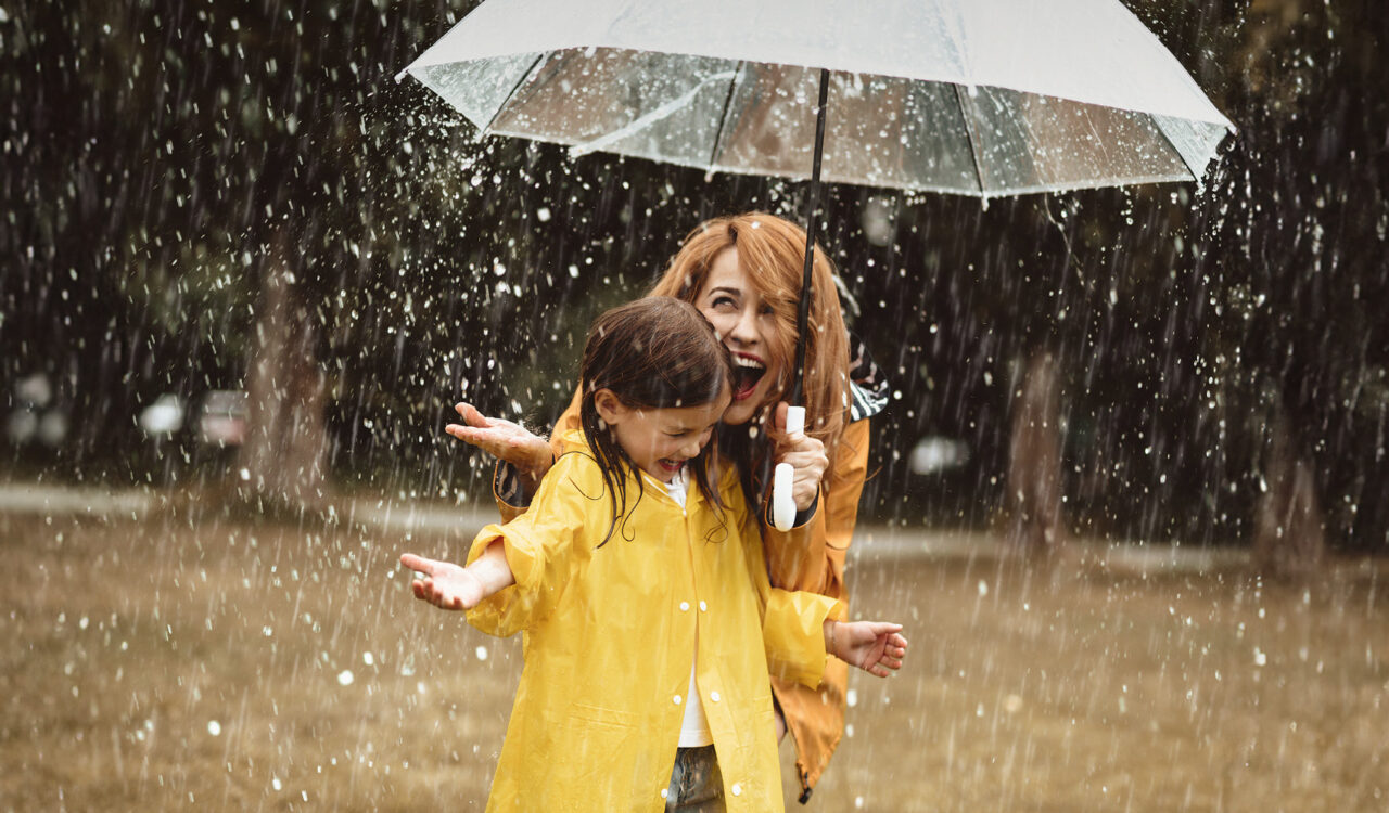 Eine Frau und ein kleines Mädchen stehen unter einem Regenschirm