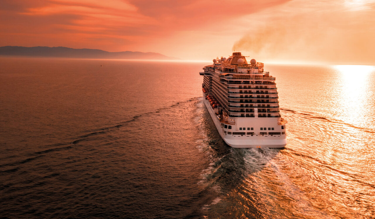 Ein Kreuzfahrtschiff fährt auf hoher See in den Sonnenaufgang