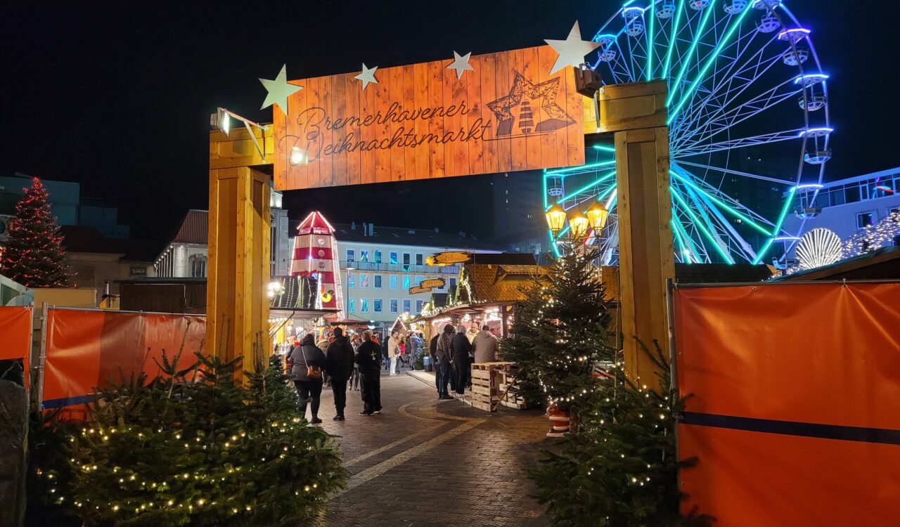 Blick auf den Eingang des Bremerhavener Weihnachtsmarkts mit Riesenrad im Hintergrund