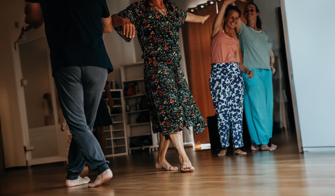 Personen in Freizeitkleidung tanzen barfuß in einer Wohnung